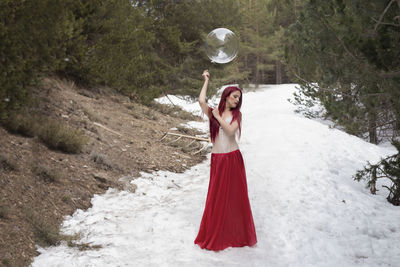 Woman with balloon standing on snowy field