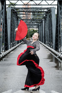 Young woman dancing on footbridge in city