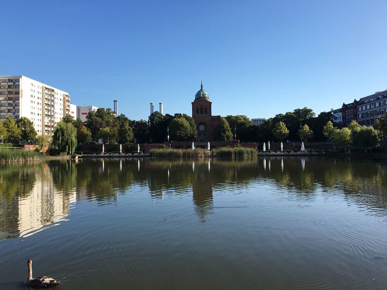SCENIC VIEW OF CALM RIVER WITH BUILDINGS IN BACKGROUND