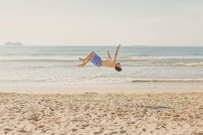 Man surfing on beach against clear sky