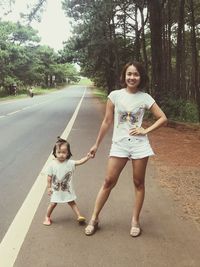 Portrait of smiling mid adult woman with daughter standing on road