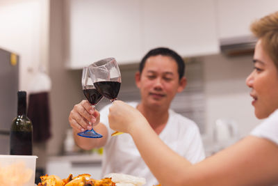 Sweet couple having dinner with toasting glasses of red wine at home.