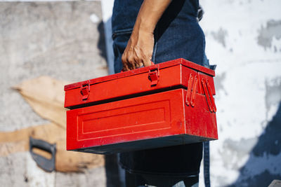 Low section of man holding red box standing outdoors