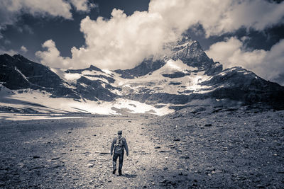 Rear view of people on snowcapped mountain against sky