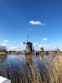 Traditional windmill by lake against sky