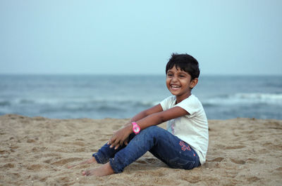 Portrait of smiling young woman sitting on beach