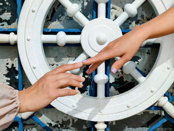 Two female hands try to touch each other with index fingers, background of symbolic steering wheel