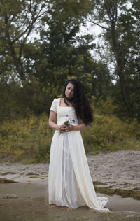 Woman standing by tree in forest