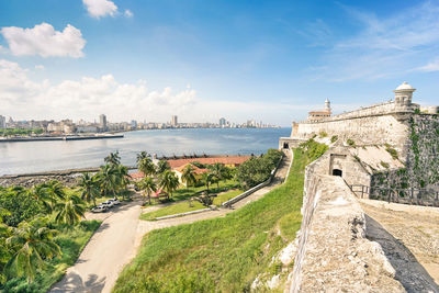 Fort by river against blue sky in city during sunny day