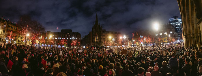 Crowd at illuminated city against sky at night