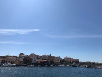 Buildings by river against blue sky