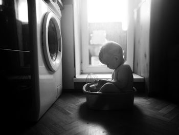 Cute boy sitting in tub at home