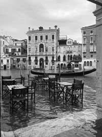 Chairs and tables by buildings in city against sky