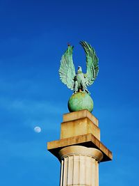 Low angle view of angel statue against blue sky