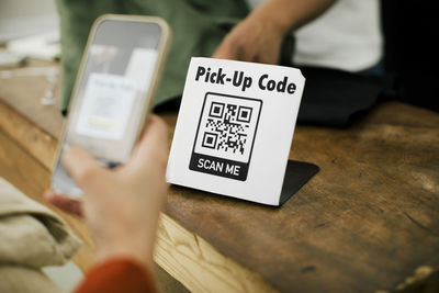 Hand woman woman scanning qr code through smart phone while doing online payment at store