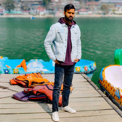 Full length of young man standing on pier by lake