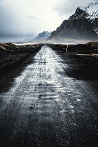 Surface level of road amidst snowcapped mountains against sky