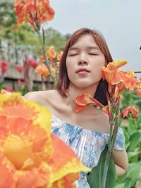 Portrait of woman standing by flowering plants