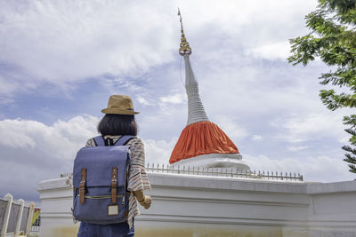 Rear view of man standing outside temple against building