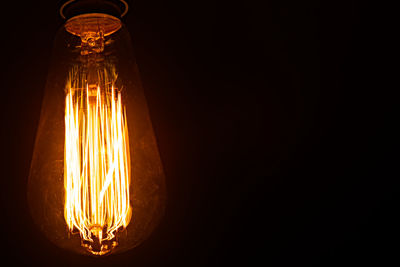 Low angle view of illuminated light bulb in darkroom