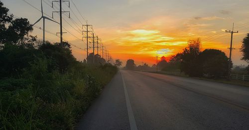 Road amidst trees against sky during sunset