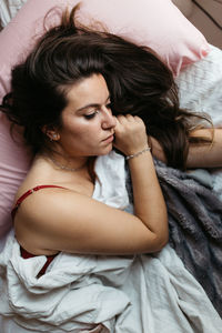 High angle view of young woman lying on bed