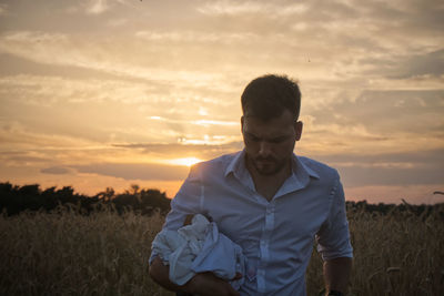 Man standing on field against sky during sunset