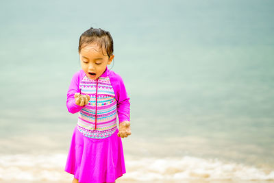 Cute girl holding sand against sea