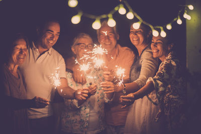 Happy friends holding sparklers at night