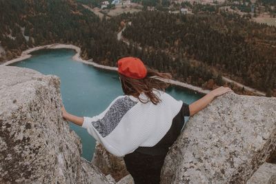 Rear view of young woman standing on mountain over lake