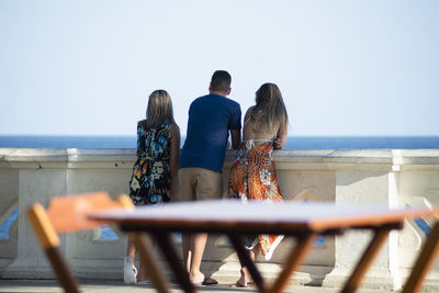 Rear view of women looking at sea against clear sky