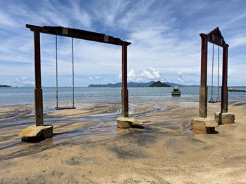 Swings at pantai pasir hitam beach against the sky in langkawi, malaysia