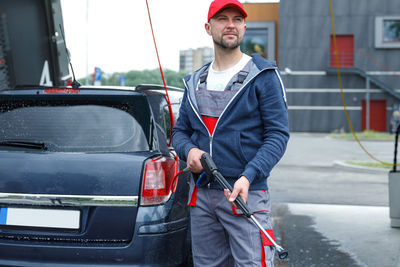 Portrait of young man standing in car