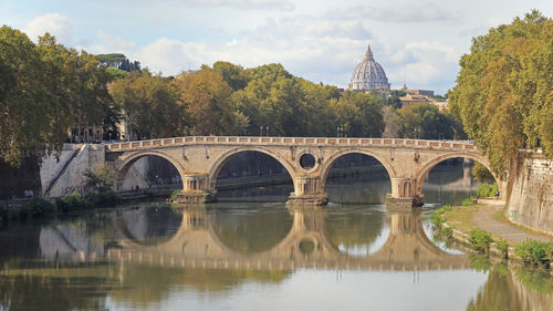 Arch bridge over river against sky