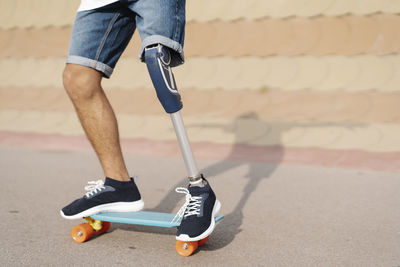 Athlete with artificial limb and foot standing on skateboard at court