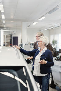 Senior couple examining car in showroom