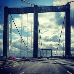 Suspension bridge against cloudy sky