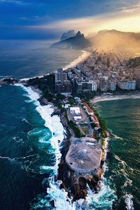 High angle view of sea and buildings against sky during sunset