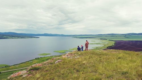 Family standing on mountain against sky