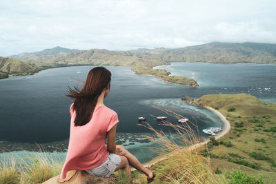 Rear view of woman looking at mountains against sky