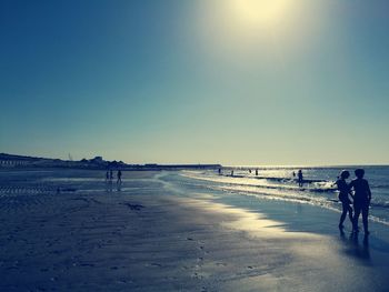 People walking on beach against clear sky