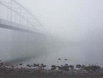 Bridge over river during foggy weather