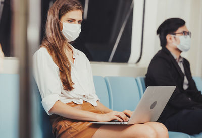 Working woman working with laptop and wearing hygienic mask prevent corona virus at sky train