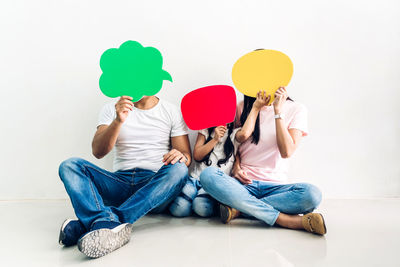 Midsection of people holding balloons against white background