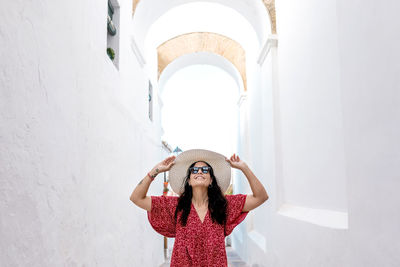 Portrait of woman standing against white wall