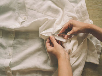 High angle view on woman cutting clothing with scissors