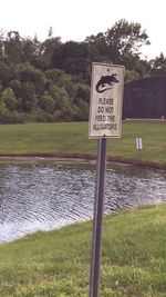 Information sign by lake against trees
