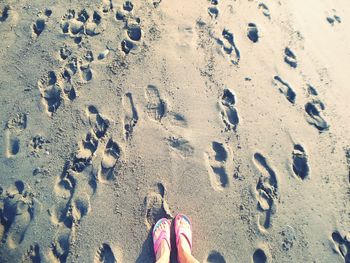 Low section of person standing on sand at beach