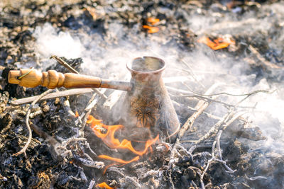 Boiling coffee in turkish cezva on campfire coals.