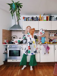 Portrait of smiling young woman with cat standing in kitchen at home